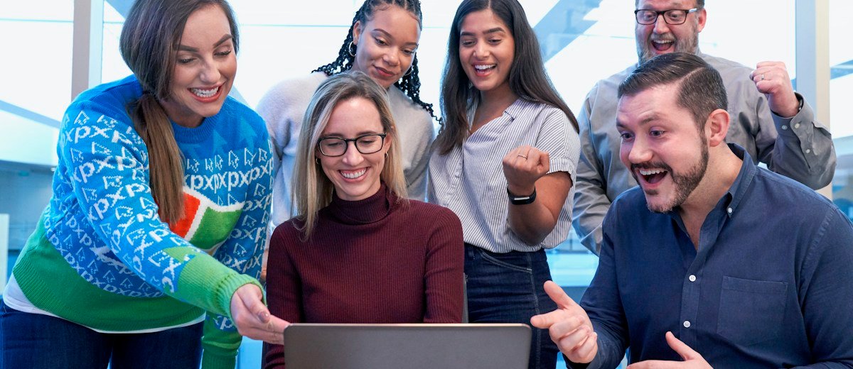 Estudiantes reunidos frente a una computadora, imagen de acceso al campus en línea